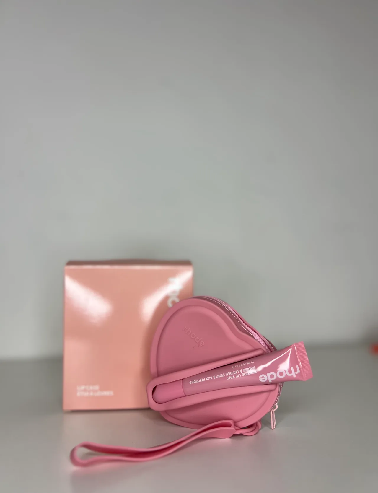 MONEDERO RHODE CON LIPGLOSS ROSA CLARO